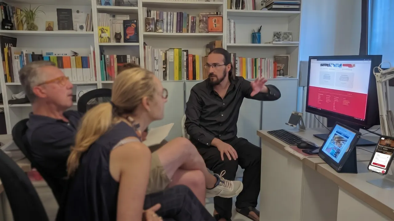 Alvise Nicoletti mostra un sito web a due persone, davanti a una libreria